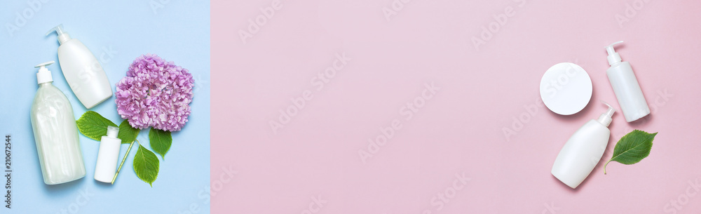 Cosmetic bottle containers with hydrangea flower on a blue and pink minimalistic background flat lay. Blank label for branding mock-up. Natural beauty product concept. Cosmetic bottle containers with hydrangea flower on a blue and pink minimalistic background flat lay. Blank label for branding mock-up. Natural beauty product concept.