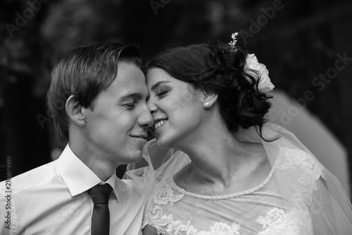 Black and white photo of joyful groom and bride, enjoying their wedding day, admiring each other after wedding ceremony. Marriage concept.