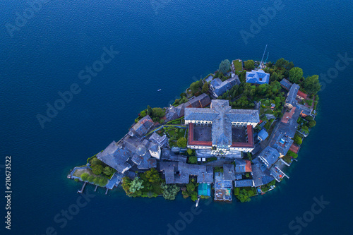 The very suggestive and romantic island of San Giulio in Orta lake, Piedmont, Italy. Aerial view at dusk.