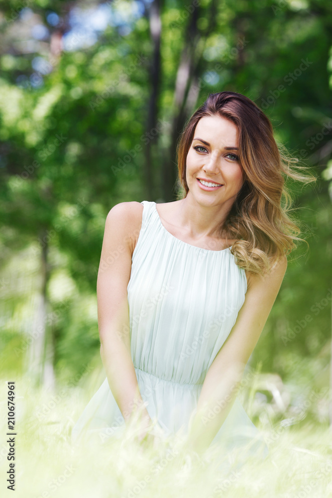 young woman in blue dress sitting on grass young woman in blue dress sitting on grass