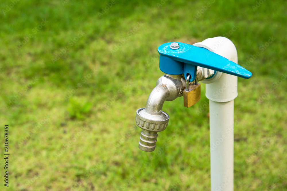 Faucet with key lock with grass field background Faucet with key lock with grass field background