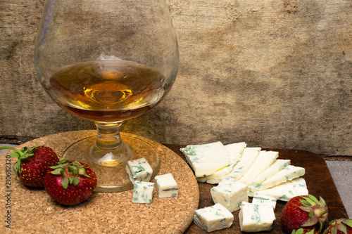 Still life with Cognac and french blue cheese, strawberry on a wooden board photo