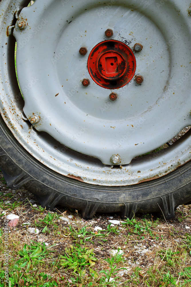 Fragment of dirty rusty old tractor wheel closeup on field. Fragment of dirty rusty old tractor wheel closeup on field.