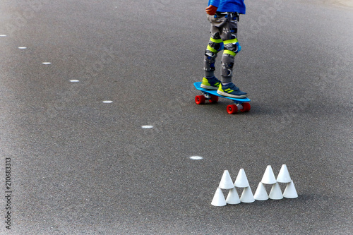 skateboarder and white cones for roller-slalom on the asphalt