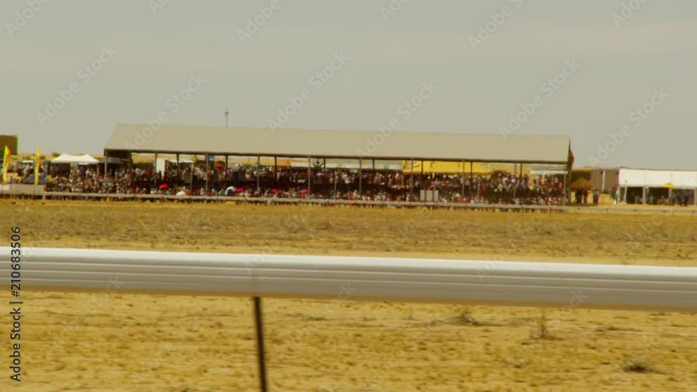 A shot from inside a car showing the stands where a horse race is taking place. The crowd is big and alive. A shot from inside a car showing the stands where a horse race is taking place. The crowd is big and alive.