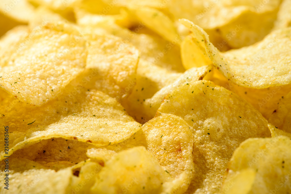 Food background of delicious chips. Corrugated golden chips pota Food background of delicious chips. Corrugated golden chips pota