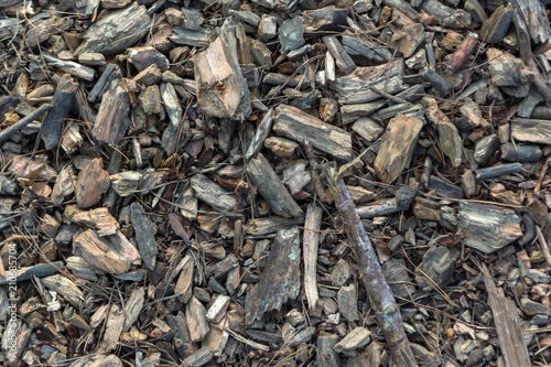 Top view of a mixture of wood chips, fragments of tree branches, spruce needles and stones lying on the ground in the forest.