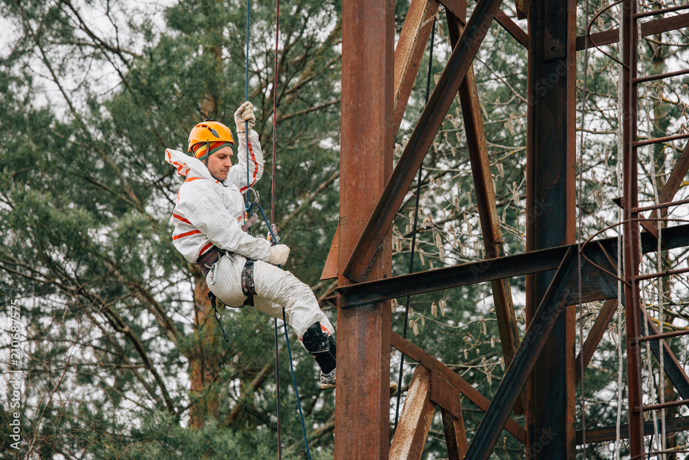 Industrial climber in uniform and helmet working on height outdoors. Professional worker doing his risky job on water tower. Industrial climber in uniform and helmet working on height outdoors. Professional worker doing his risky job on water tower.