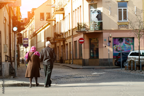 Unidentified people walking in old street of European town in ra