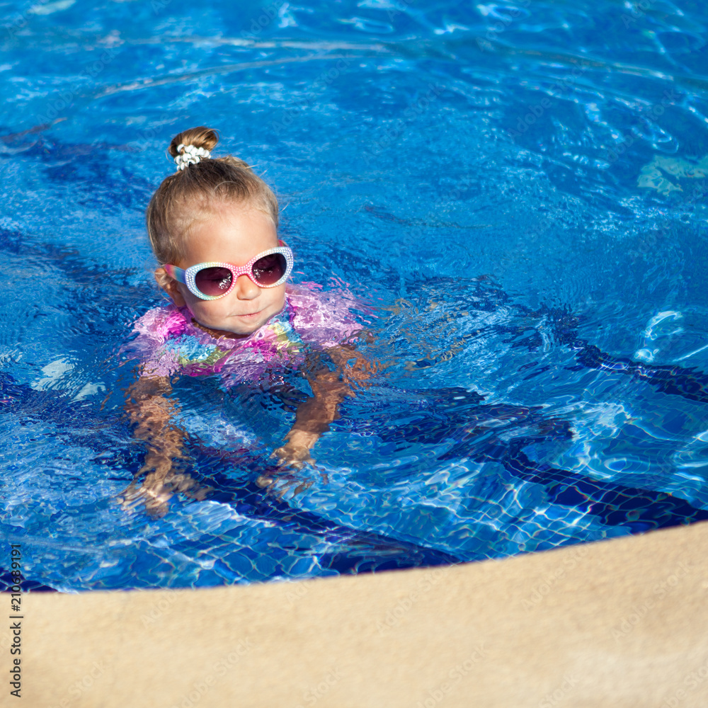 little pretty girl is swimming in pool,