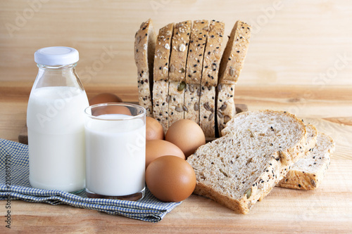 Bottle of milk, eggs, and bread on the wooden table.