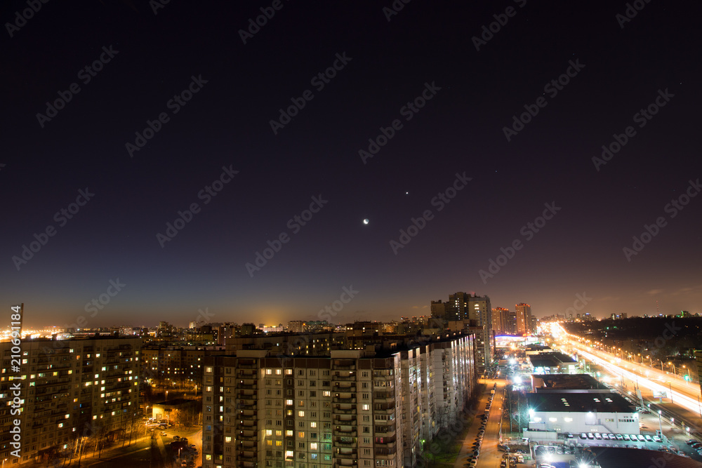 Panorama of the night city with high-rise buildings and highways, lighted lanterns