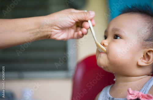 Photos An Asian baby boy eating food from feeding