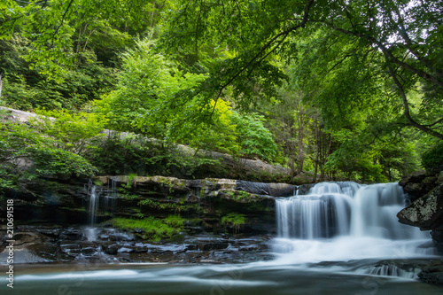 A forest waterfall with motion and large stones deep in a forest.