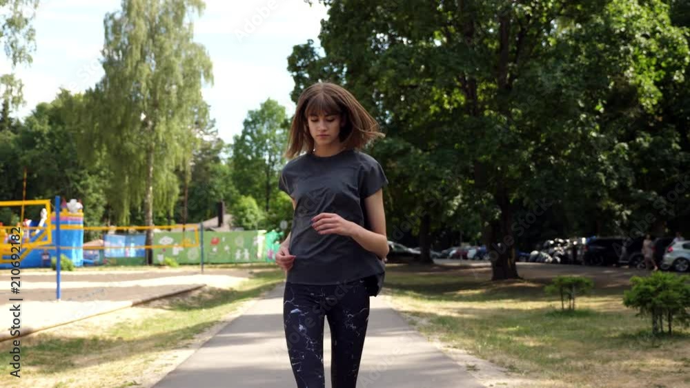 Young woman running in park, slow motion, long shot. Young woman running in park, slow motion, long shot.