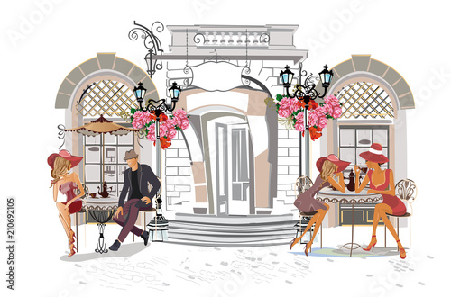 Fototapeta Ludzie mody w ulicznej kawiarni. Uliczna kawiarnia z kwiatami w starym mieście.