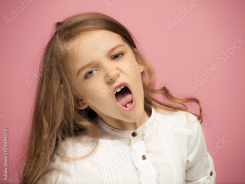 Portrait of angry teen girl on a pink studio background