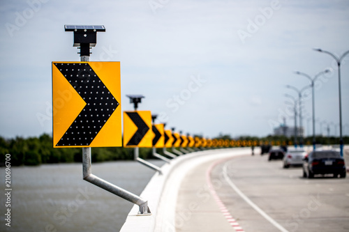 Curve road signpost with lighting on solar cell energy along the liver with cars
