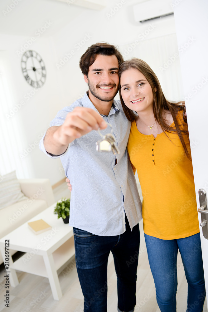 © W PRODUCTION - cheerful young couple man and woman welcome friends at open front door new student home apartment © W PRODUCTION - cheerful young couple man and woman welcome friends at open front door new student home apartment