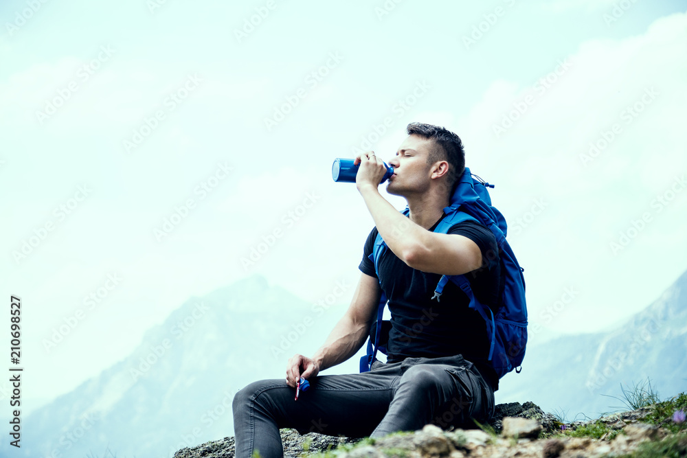 Thirsty male hiker drinking water and enjoying the view