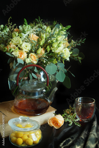 Still-life with a bouquet of flowers and a kettle and candies in a jar