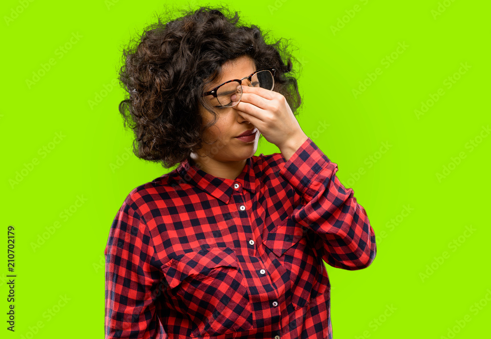 Beautiful arab woman with sleepy expression, being overworked and tired, rubbes nose because of weariness Beautiful arab woman with sleepy expression, being overworked and tired, rubbes nose because of weariness
