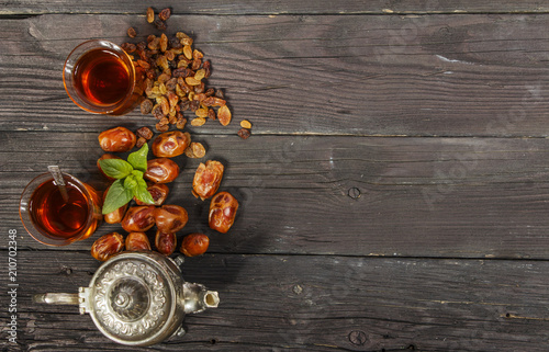 Traditional Arabic, Turkish Ramadan tea with dry dates and raisins on a wooden black table. Ramadan. Turkish fresh tea with dates. View from above. 