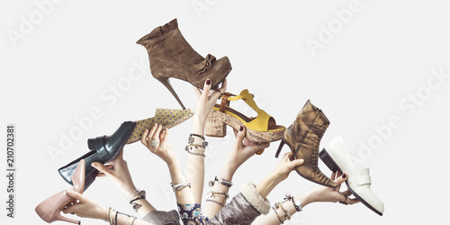 Hands holding different shoes on isolated background