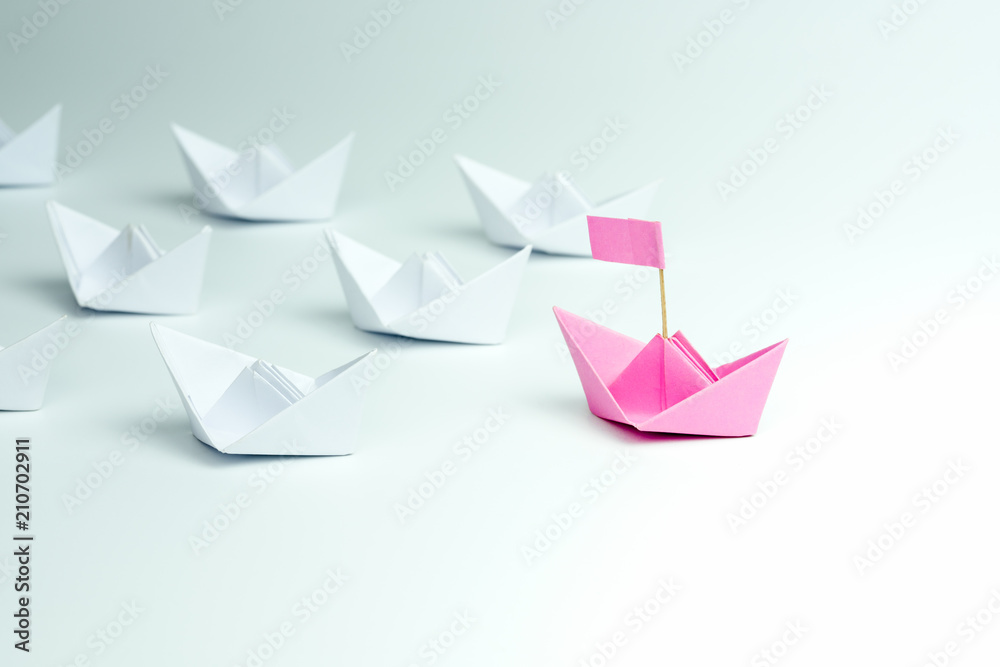 Woman Leadership concept with pink paper ship leading among white on white background. Woman Leadership concept with pink paper ship leading among white on white background.