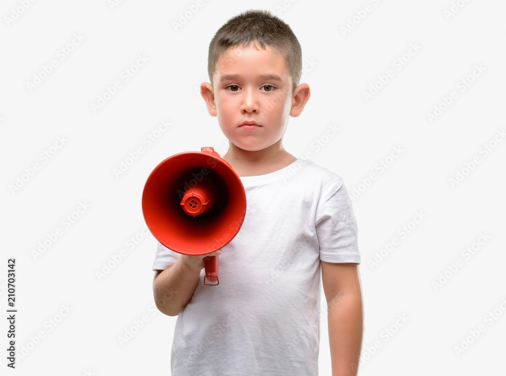 Dark haired little child holding megaphone with a confident expression on smart face thinking serious Dark haired little child holding megaphone with a confident expression on smart face thinking serious