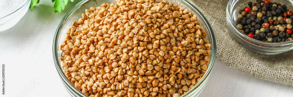 Raw buckwheat in glass bowls on sackcloth on a wooden background. Healthy diet food. Raw buckwheat in glass bowls on sackcloth on a wooden background. Healthy diet food.