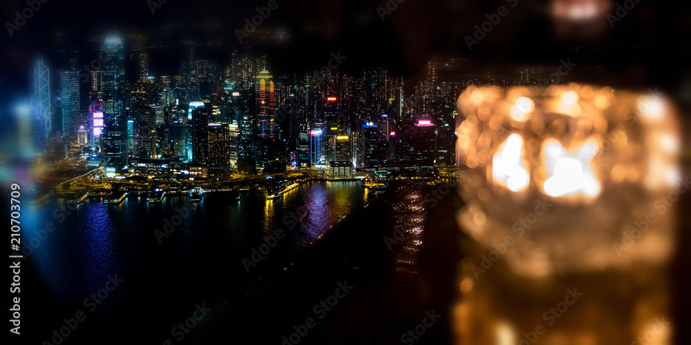 Blured burning candle in glass cup with Hong Kong island night view background