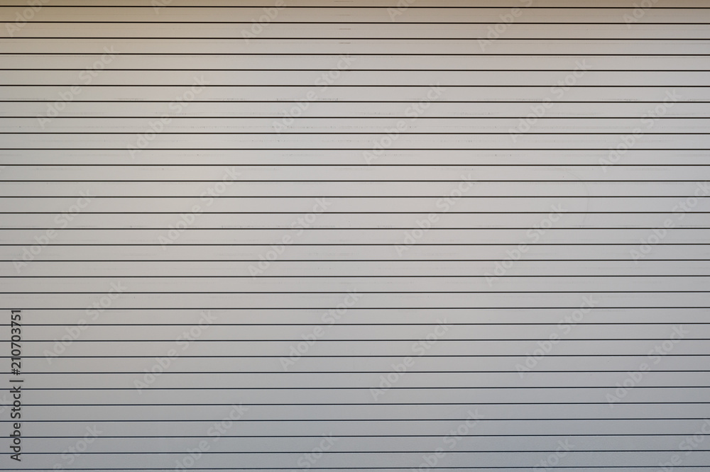 A closeup shot of automatic metal roller door used in factory, storage, garage, and industrial warehouse. The corrugated and foldable metal sheet offer space saving and provide urban and rustic feel A closeup shot of automatic metal roller door used in factory, storage, garage, and industrial warehouse. The corrugated and foldable metal sheet offer space saving and provide urban and rustic feel