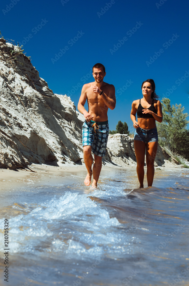 two athletes, a boy and a girl, play sports on the beach. guy black girl Asian. jog along the shore