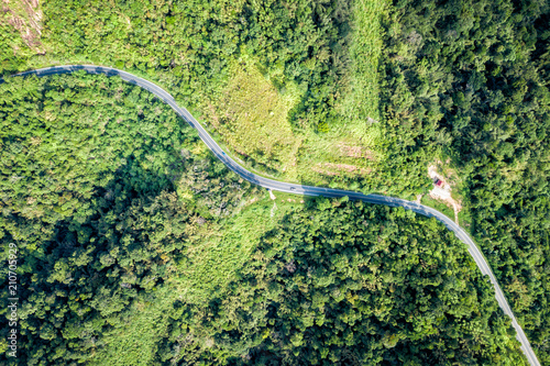 Top view beautiful rural road on the deep forest mountain. Amazing nature landscape. Aerial view from flying drone.