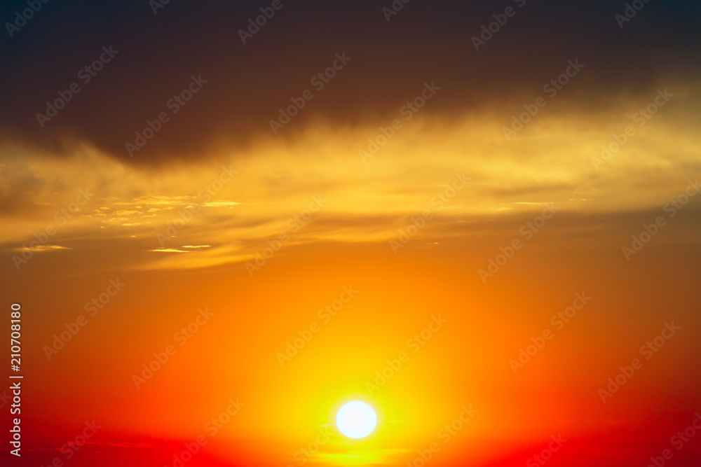 The setting sun against a background of dark clouds