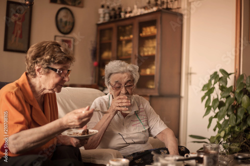 Positive female pensioners drinking coffee and chatting.