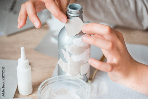 secondary use of paper debris. children's handmade from papier mache. The baby's hands are glued to pieces of paper on the bottle. photo