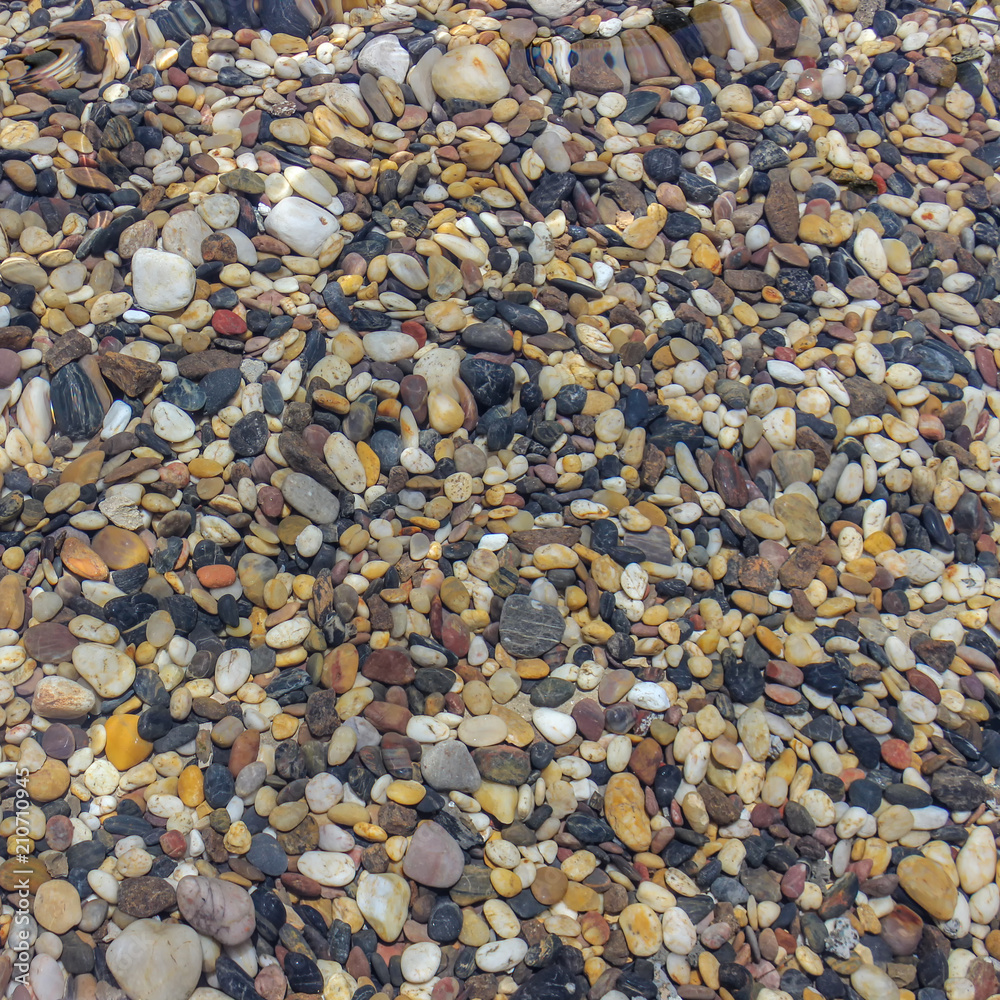 sea stones under blue water. Background of small multicolored stones lying under water. sea stones under blue water. Background of small multicolored stones lying under water.
