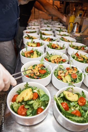 Hands preparing a shrimp salad at an industrial kitchen