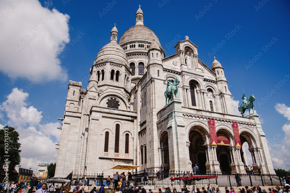 Paris, France - August 10, 2017. Sacre Coeur basilica or Basilica of the Sacred Heart of Paris on the top of Montmartre hill with people around. Old Roman Catholic church, popular touristic landmark.