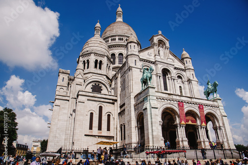 Paris, France - August 10, 2017. Sacre Coeur basilica or Basilica of the Sacred Heart of Paris on the top of Montmartre hill with people around. Old Roman Catholic church, popular touristic landmark. © krugli