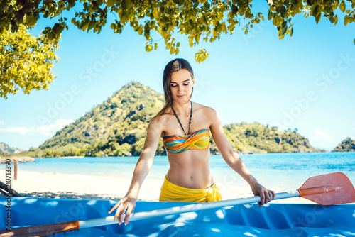 Woman in bikini with a kayak on an island in front of beach