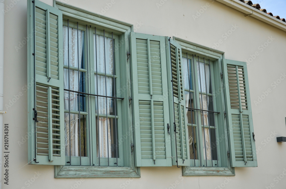 Fototapeta premium Old light green wooden windows with shutters in Mediterranean style. Vintage background. Cyprus, Nicosia.