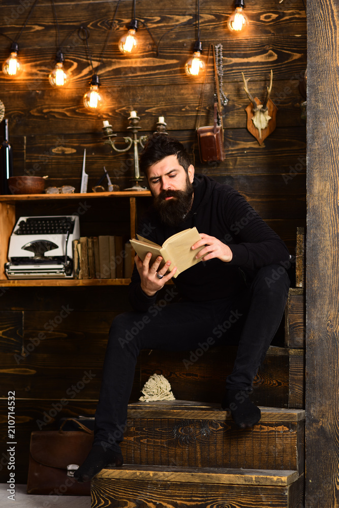 Best weekend. Man with beard holds old book and read. Guy in cozy warm atmosphere relaxing while reading Man bearded enjoy evening with favourite literature, wooden background