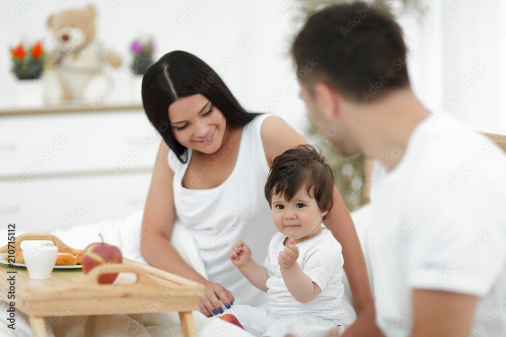 Family taking the breakfast on the bed in the bedroom Family taking the breakfast on the bed in the bedroom