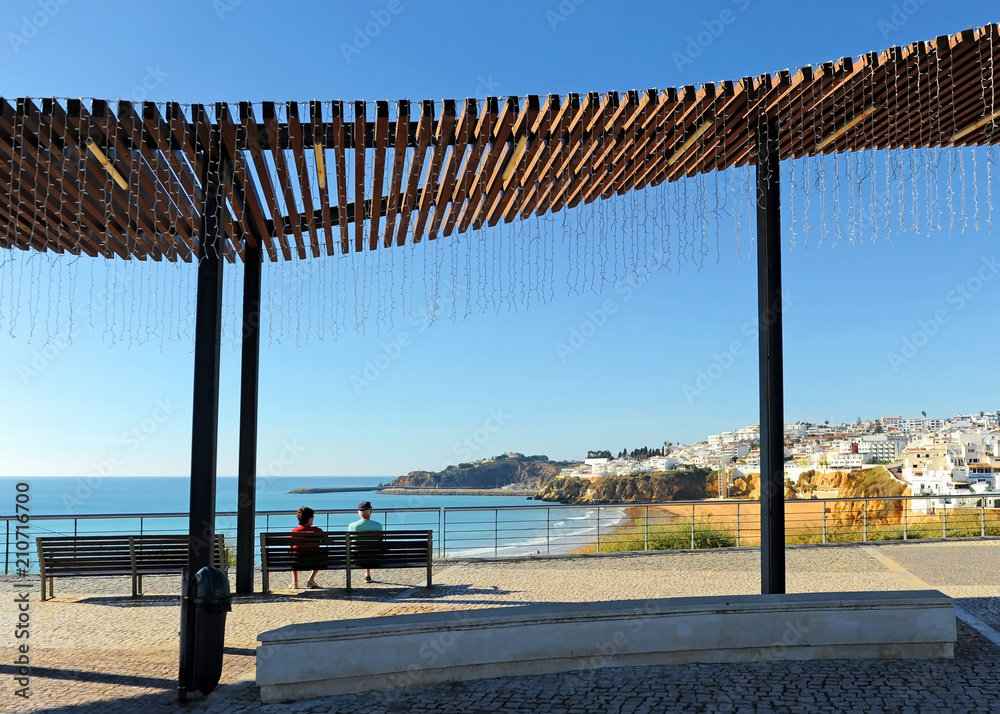Dos turistas de edad avanzada sentados en un banco en la playa de Albufeira, uno de los más visitados por el turismo europeo. Algarve, al sur de Portugal.