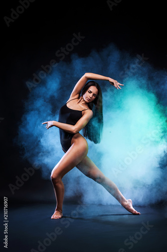Beautiful young and fit ballet dancer jumping on a black background. Dance and sport concept.