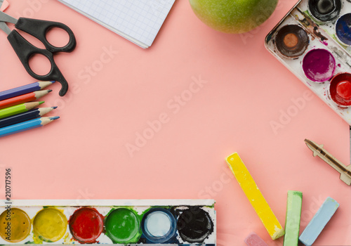 flatlay with school supplies, watercolor, scissors, colored pencils, sheets of paper, colored pencils, green apple 