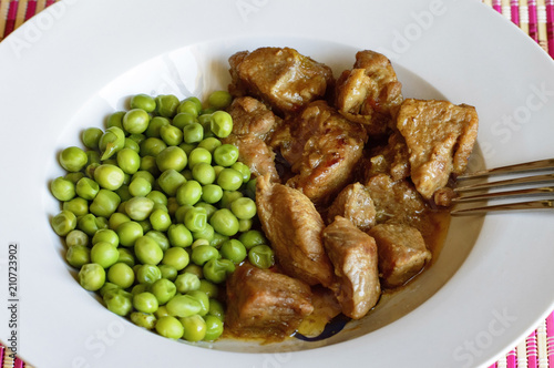 Primer plano de un plato de carnes estofada con guisantes en un plato blanco. photo